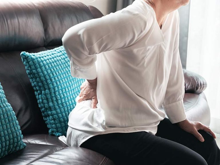 woman pressing on her lower back with her hand