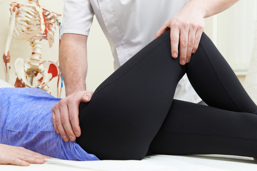 doctor treating patient for back pain by flexing his leg up against himself
