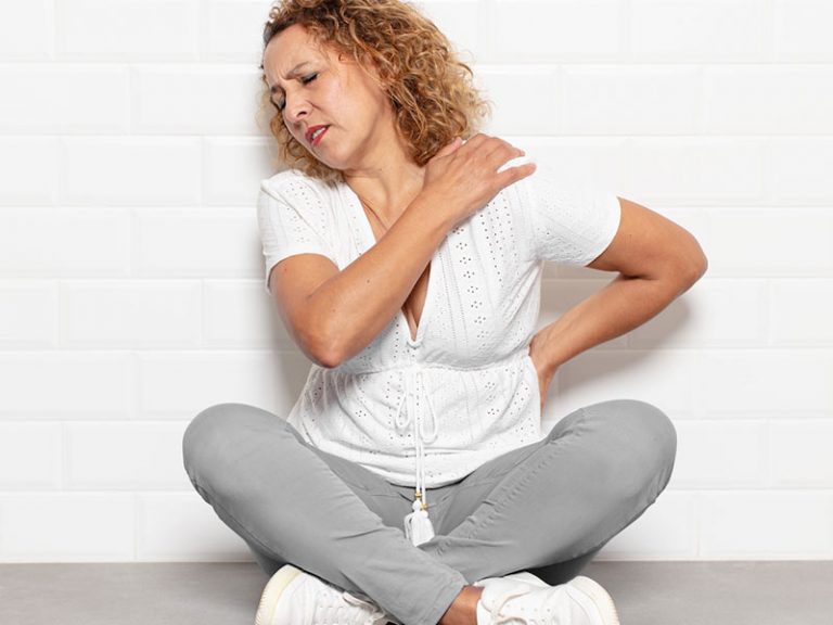 woman try to soothe her own back pain