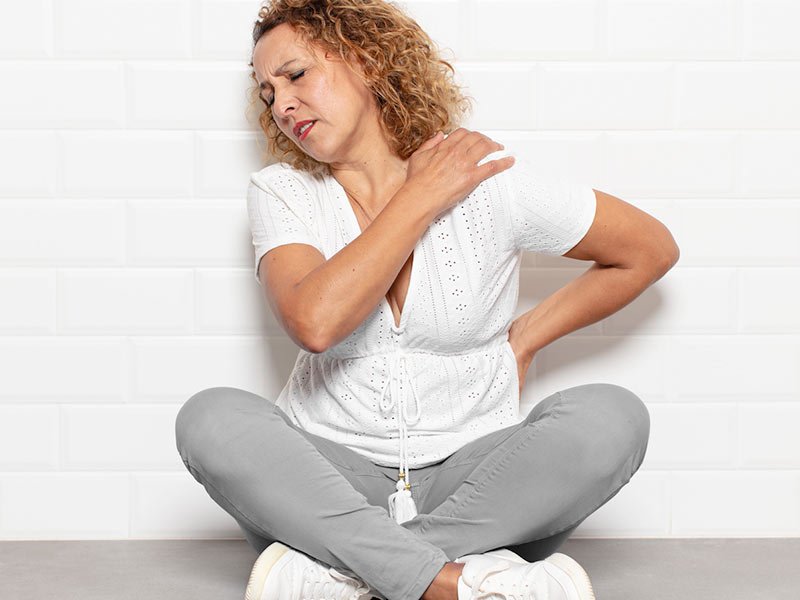 woman try to soothe her own back pain